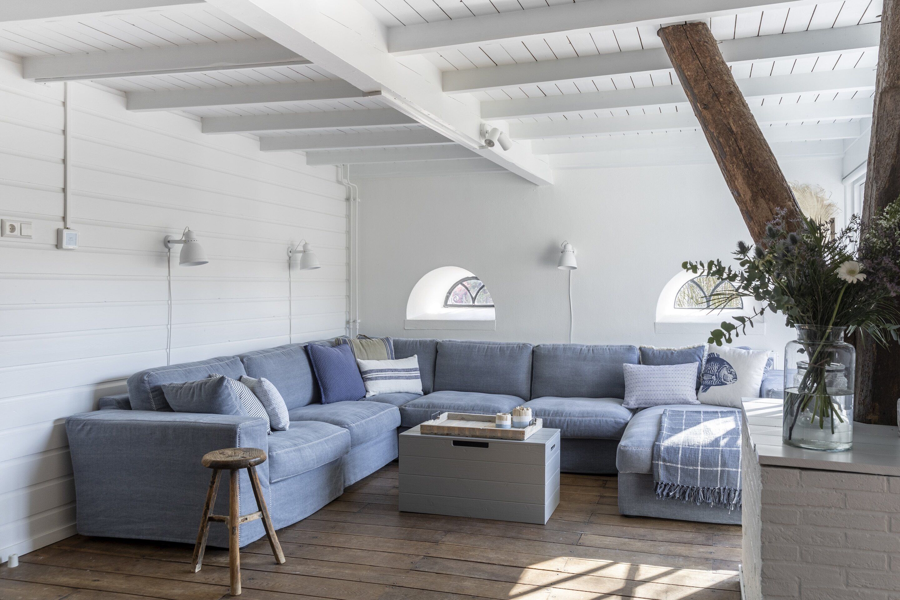 A modern living room with a sectional sofa, a wooden stool, and a coffee table.