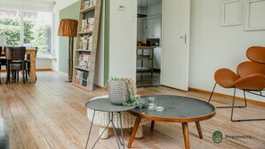 Ett modernt vardagsrum med ett runt bord, en bokhylla och en matplats.