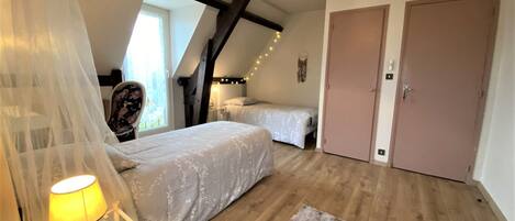 Un dormitorio con dos camas, piso de madera, un pequeño tapete, una lámpara y un aplique de techo.