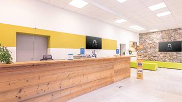 Un espace d’accueil doté d’un comptoir de réception en bois, d’un mur en pierre et d’une décoration aux couleurs jaune et blanche.