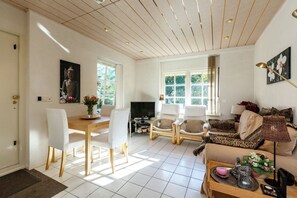 A spacious living room with a dining area, a television, and a sofa with patterned cushions. - Apartment in Oostkapelle Near the Beach (Oostkapelle)