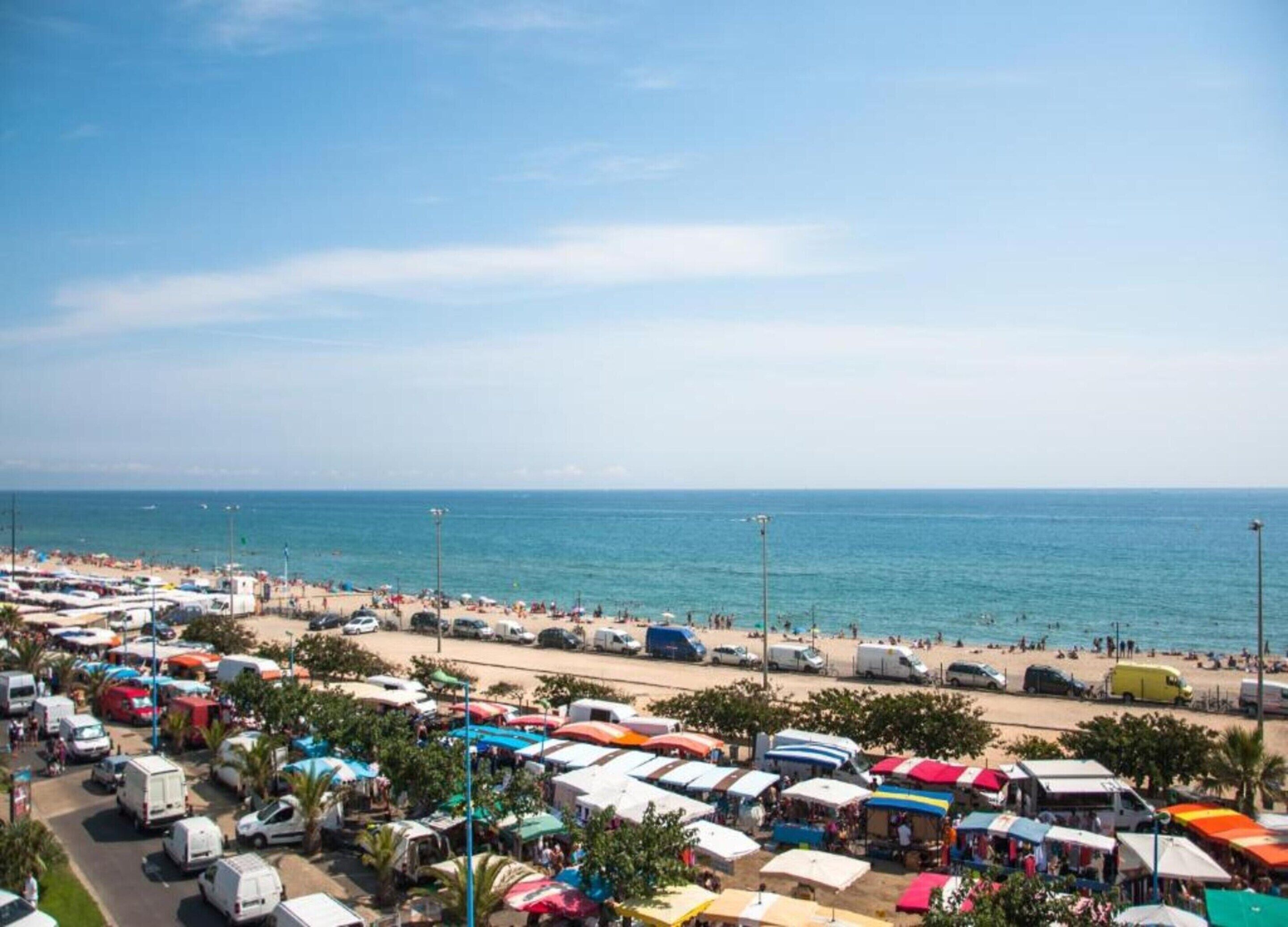 Eine Küstenregion mit vielen Zelten und Fahrzeugen, was auf ein Camping- oder Festivalambiente hindeutet.