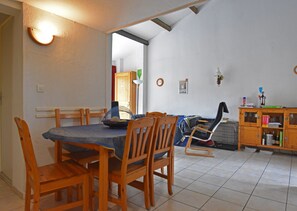 A dining area with wooden chairs and a table, a small cabinet with bottles, and a tiled floor. - Great Holiday Home Near a Pleasure Marina, the Mediterranean and the Pyrenees (Saint-Cyprien)