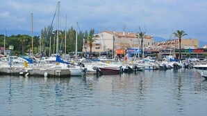 A marina with boats docked, a building with signage, and a mountainous backdrop. - Great Holiday Home Near a Pleasure Marina, the Mediterranean and the Pyrenees (Saint-Cyprien)