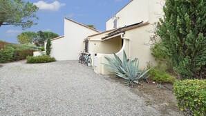 A building with a gravel driveway, a covered entrance, and a bicycle parked outside. - Great Holiday Home Near a Pleasure Marina, the Mediterranean and the Pyrenees (Saint-Cyprien)