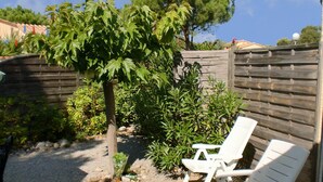 A wooden deck with two white lounge chairs, surrounded by a wooden fence and various green plants. - Great Holiday Home Near a Pleasure Marina, the Mediterranean and the Pyrenees (Saint-Cyprien)