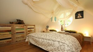 A bedroom with a canopy bed, wooden floor, and a window with curtains. - Cozy Countryside Escape in Dalfsen (Dalfsen)