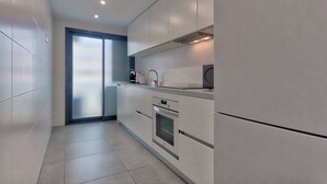 Eine moderne Küche mit weißen Schränken, einem eingebauten Ofen und einem großen Fenster.