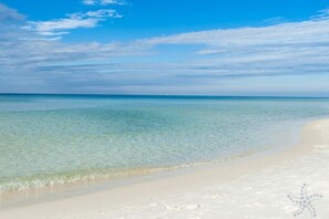 Une plage à l’eau turquoise et limpide, bordée d’un rivage sablonneux.