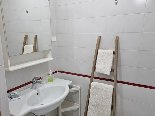 A bathroom with a white sink, mirror, and wooden towel rack.
