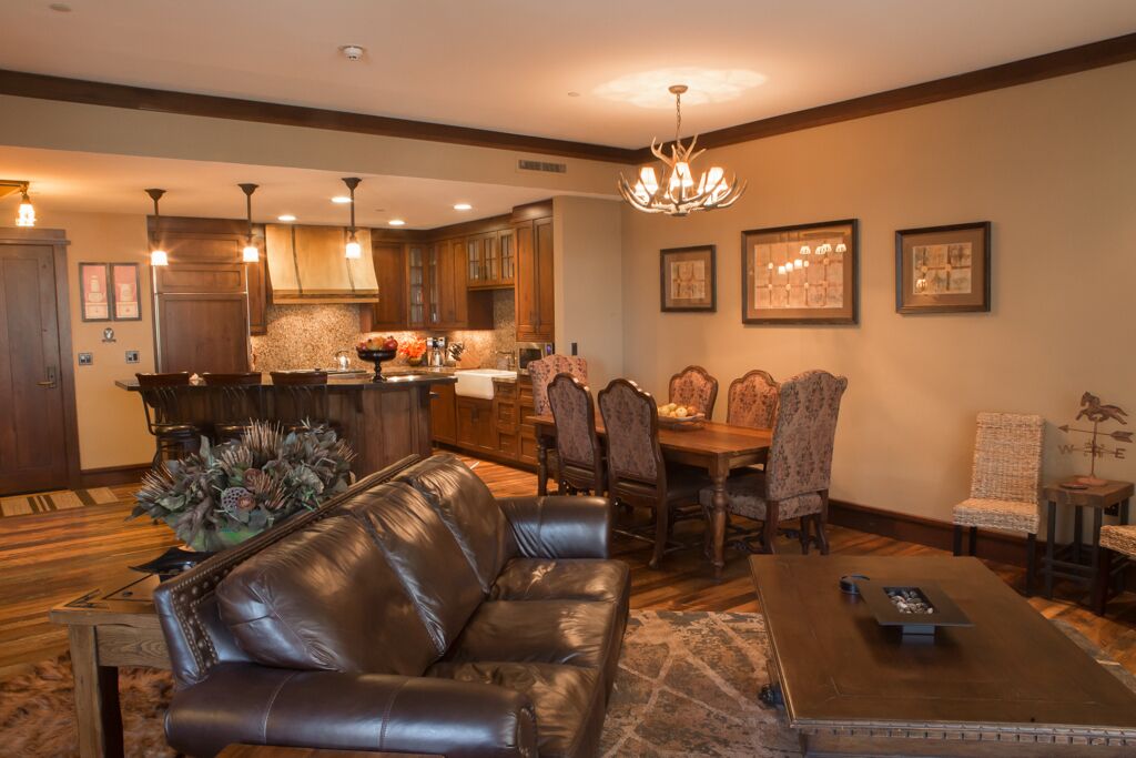 A spacious living room with a leather sofa, a coffee table, and a dining area with a chandelier.