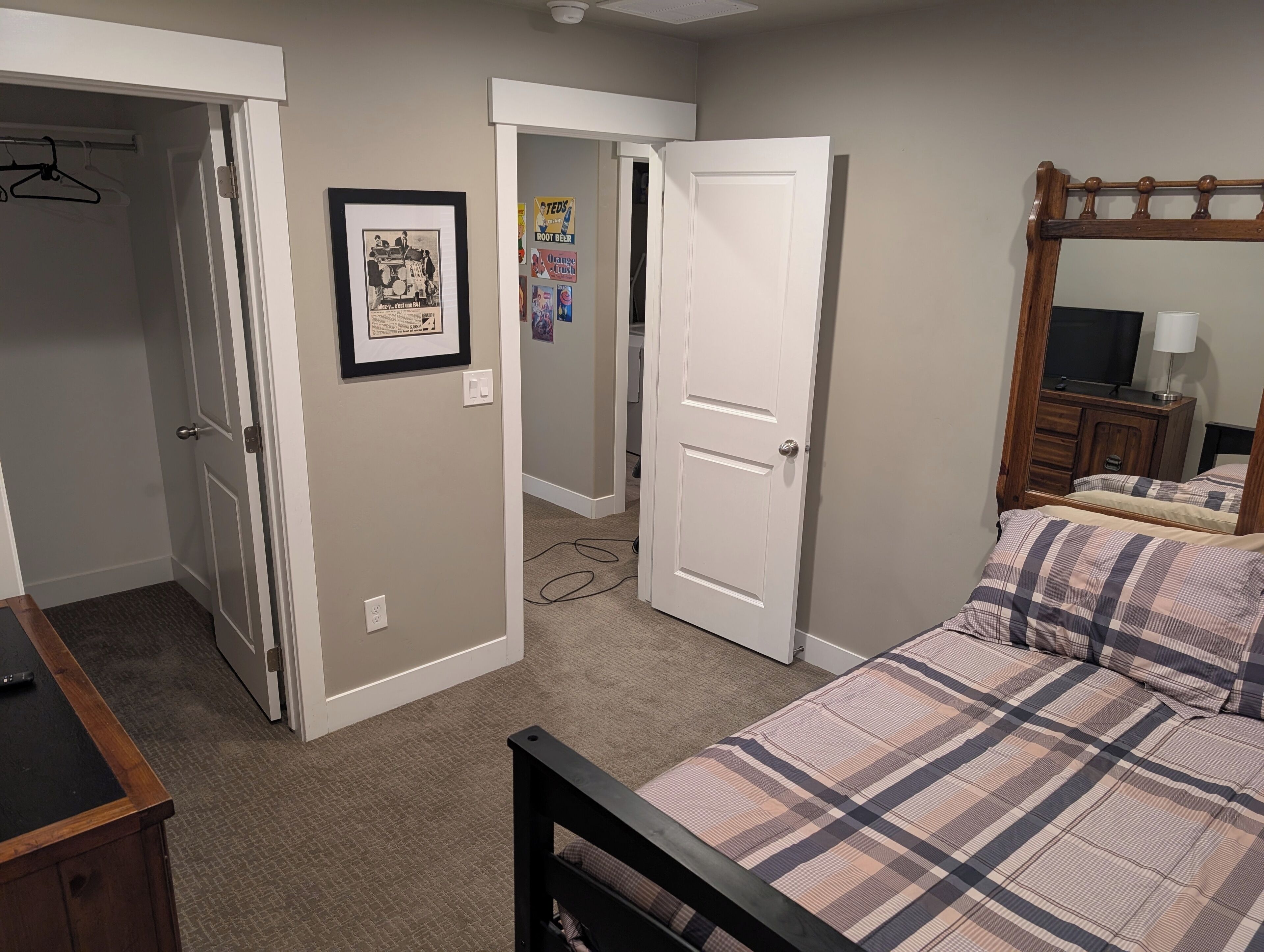 Une chambre à coucher comprenant un lit, une commode, un miroir et une porte donnant sur une autre pièce.