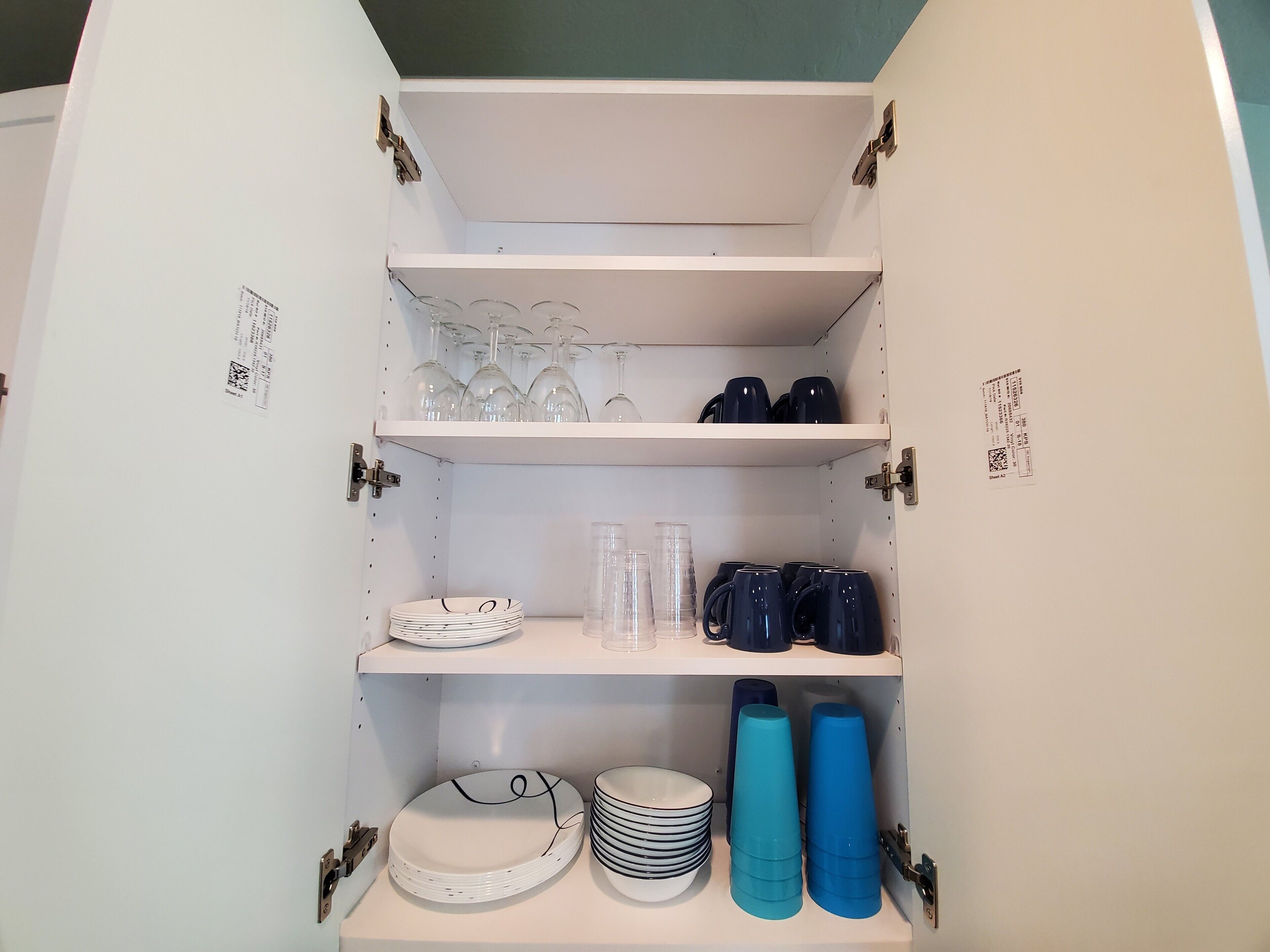 Ein Schrank mit Regalen, der Teller, Gläser und Tassen beherbergt.