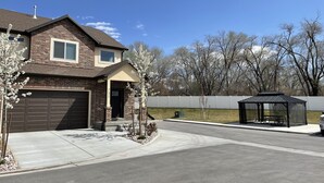 Una casa de dos pisos con garaje, un porche cubierto y un patio cercado.