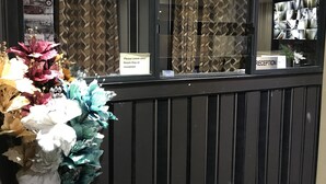 Ett receptionsområde med en mönstrad gardin, en klocka och en skylt som uppmanar besökare att lämna in nycklarna till rummet i receptionen.