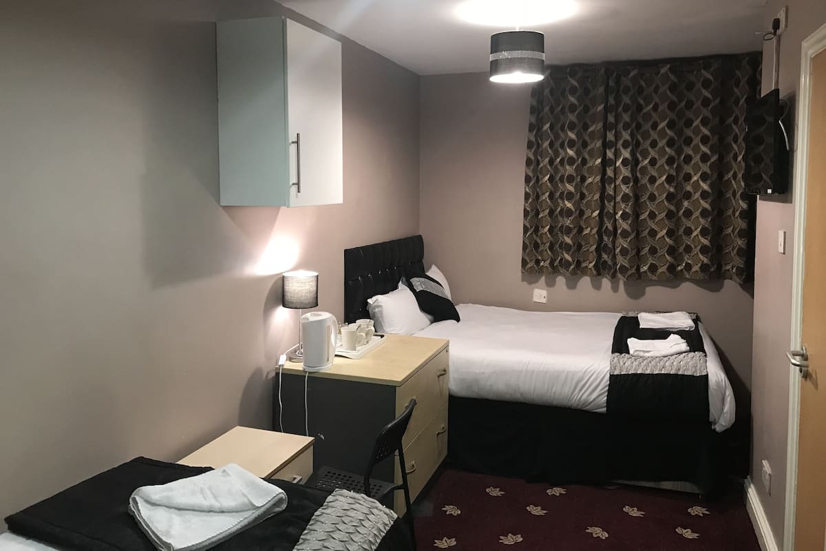 Una habitación de hotel con cama, escritorio, silla, lámpara y televisor.