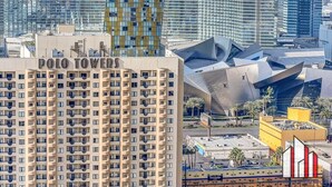 A high-rise building with the sign "POLO TOWERS" and a modern architectural structure in the background.