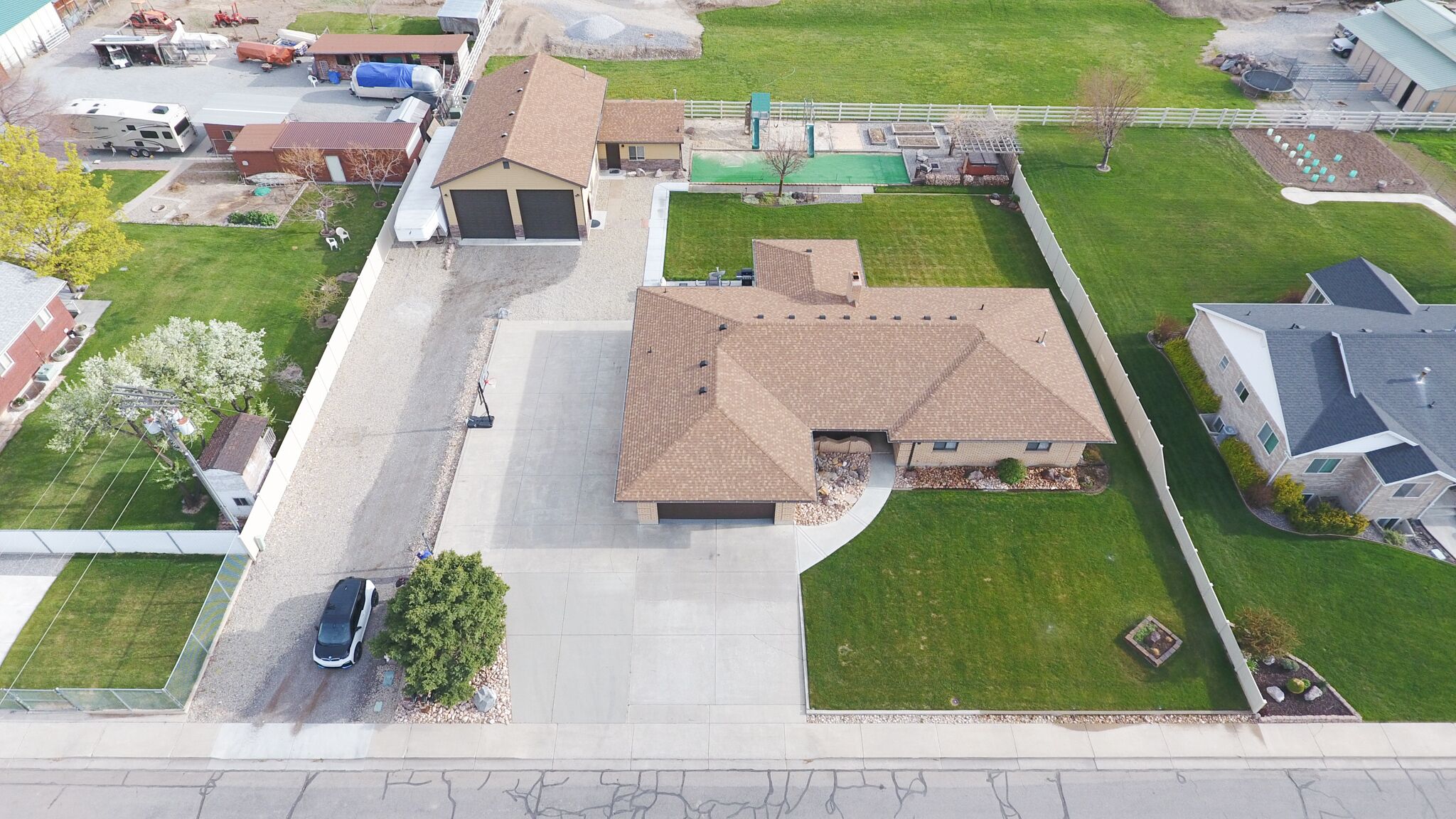 An aerial view of a residential area with houses, a driveway, and a lawn.