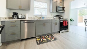 Una cocina moderna con gabinetes grises, electrodomésticos de acero inoxidable y un ventanal que proporciona luz natural.