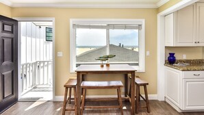 Une cuisine donnant sur la plage, avec des tabourets en bois et une table.