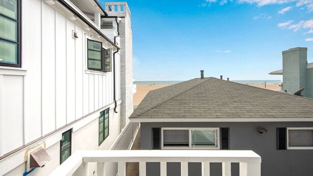 Un bâtiment à l’extérieur blanc, avec un toit gris et un balcon doté de balustrades blanches.