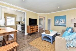 A living room with a wooden dining table, a blue sofa, and a television.