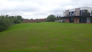 Guests can enjoy a balcony with outdoor seating amidst a serene grassy field and lush greenery.