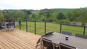 Enjoy a serene view of the lush landscape from this outdoor deck, complete with a table and chairs.