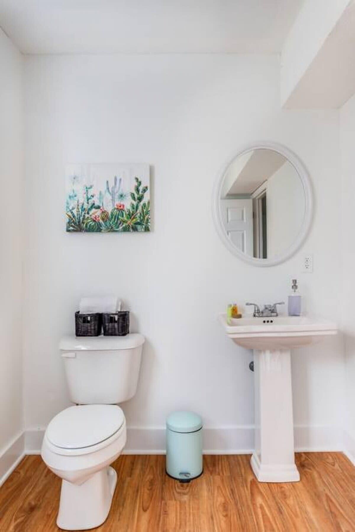 A small, white bathroom with a toilet, a sink, and a trash can.