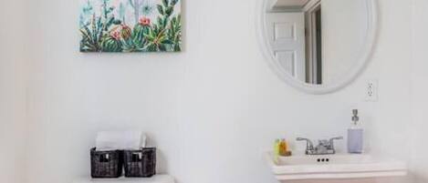 A small, white bathroom with a toilet, a sink, and a trash can.