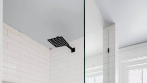 A modern bathroom with white subway tiles, a glass shower enclosure, and a hexagonal tile floor. - Charming 2bd Downtown Suite (Charleston)