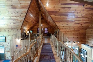 A wooden interior with a central staircase, wooden railings, and a view of the upper floor.