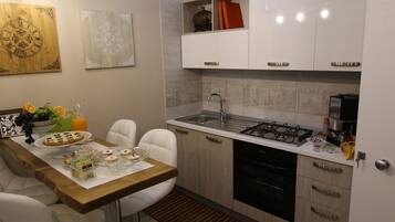 Una cucina moderna con mobili bianchi, un piano di lavoro in legno e un'area pranzo con sedie bianche.