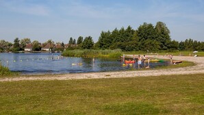 Une zone au bord d’un lac où l’on peut pratiquer des activités nautiques, une plage de sable et un paysage boisé en arrière-plan.