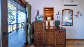 A wooden cabinet with a television, a framed picture, and a small shelf with decorative items. - Mangrove Suite - 2nd Floor Double (West End)