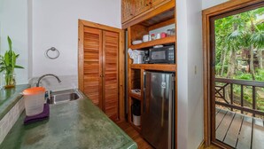 A compact kitchen with wooden cabinets, a stainless steel refrigerator, and a microwave. - Port Royal Suite - Ground Level King (West End)