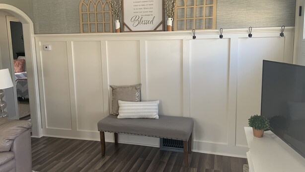 A room with a bench, a wall-mounted sign, and a potted plant.