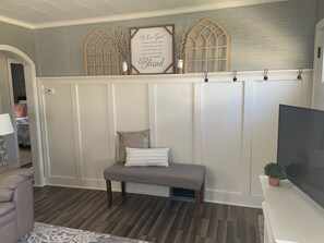 A room with a bench, a wall-mounted sign, and a potted plant.