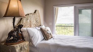 A bedroom with a bed, a lamp, a bear sculpture, and a view of the outdoors. - Walk to Gruene Hall!On Guadalupe River! Pets Welcome (New Braunfels)
