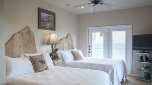 A hotel room with two beds, a ceiling fan, a television, and a door with blinds. - Walk to Gruene Hall!On Guadalupe River! Pets Welcome (New Braunfels)