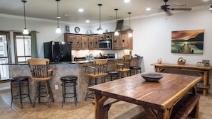 A kitchen with wooden cabinets, a central island with stools, a dining table, and a ceiling fan. - Walk to Gruene Hall!On Guadalupe River! Pets Welcome (New Braunfels)