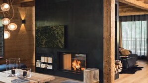Una sala de estar acogedora con chimenea, vigas de madera y un sofá moderno.