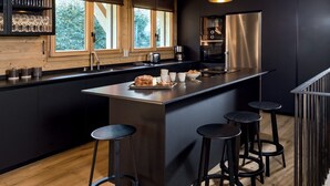 Una cocina moderna con una isla central, taburetes negros y luces colgantes.