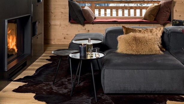 Un salón acogedor con chimenea, un sofá y vistas a montañas nevadas.