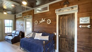 A bedroom with a bed, a wooden ceiling, a door, and a sign on the wall.