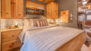 Un dormitorio con una cama, armarios de madera, un cartel y una mesita de noche con una lámpara.