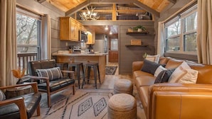 Un interior acogedor con techo de madera, una zona de cocina, una sala de estar con sofás de cuero y un comedor.