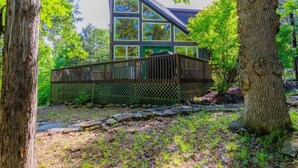 A modern cabin with a sloped roof, surrounded by trees and a stone pathway.