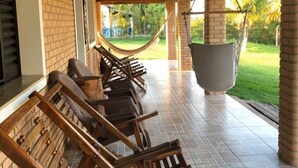 Un área de patio techada con sillones de madera y una hamaca.