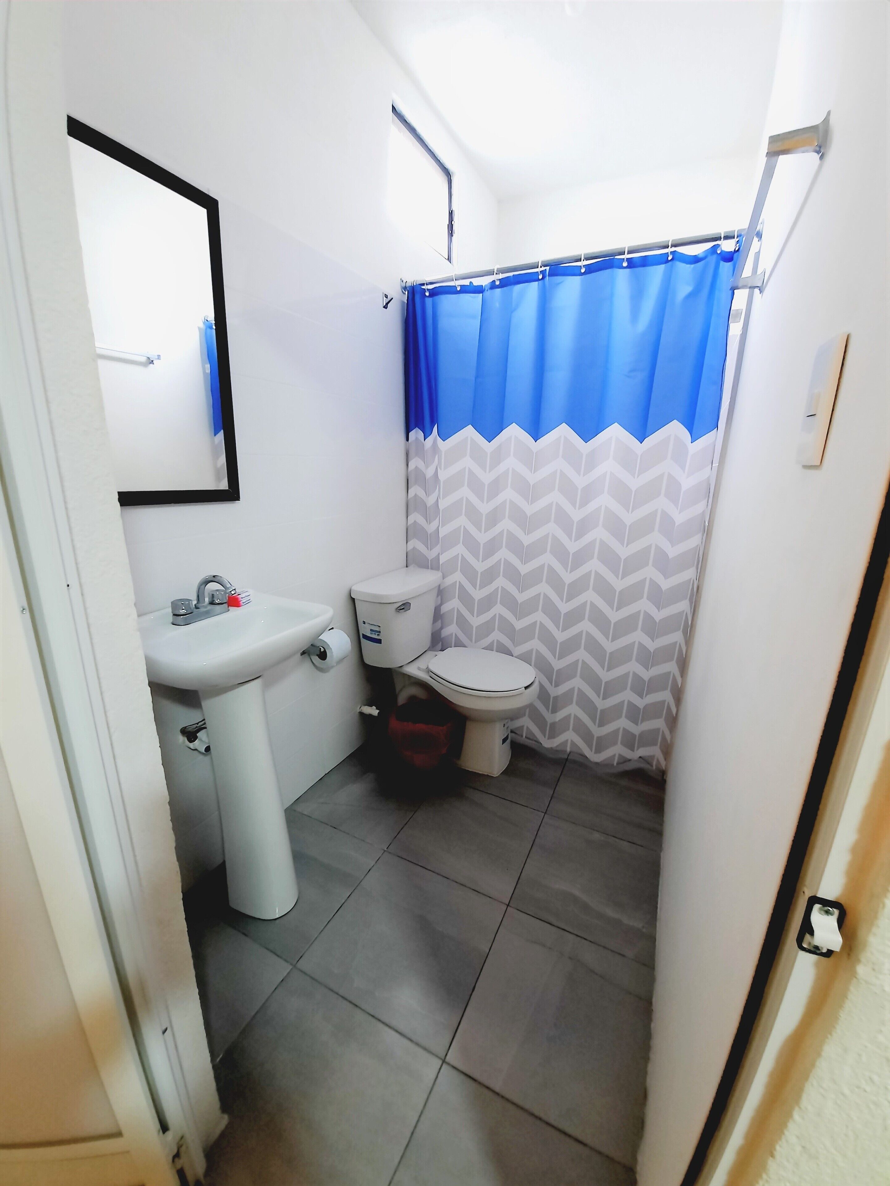 A small, compact bathroom with a toilet, sink, and shower curtain.